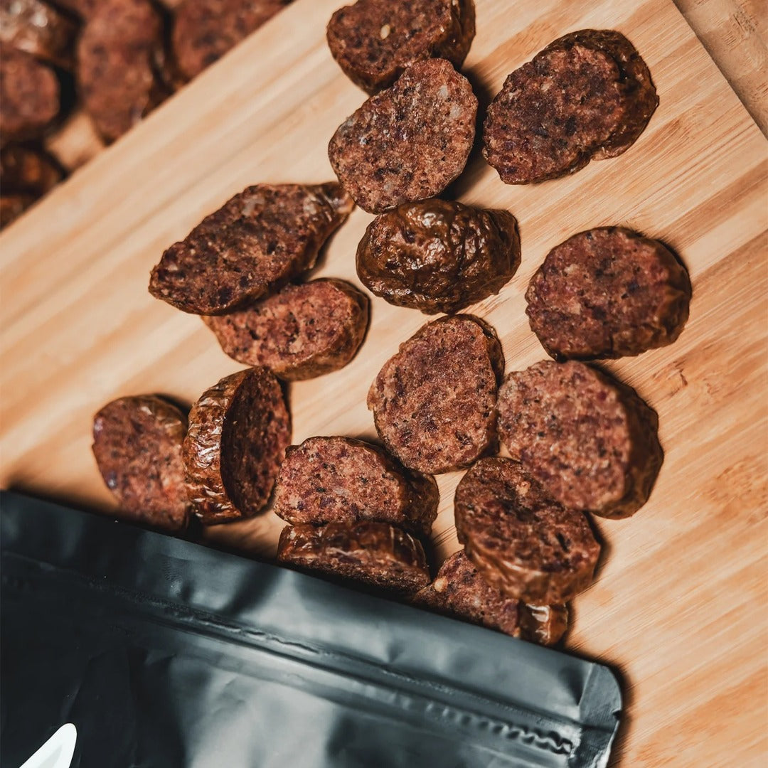 Oxtail Bites spilling from a black pouch onto a wooden cutting board